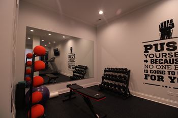 A gym room with a wall that says "push yourself" and a mirror.
